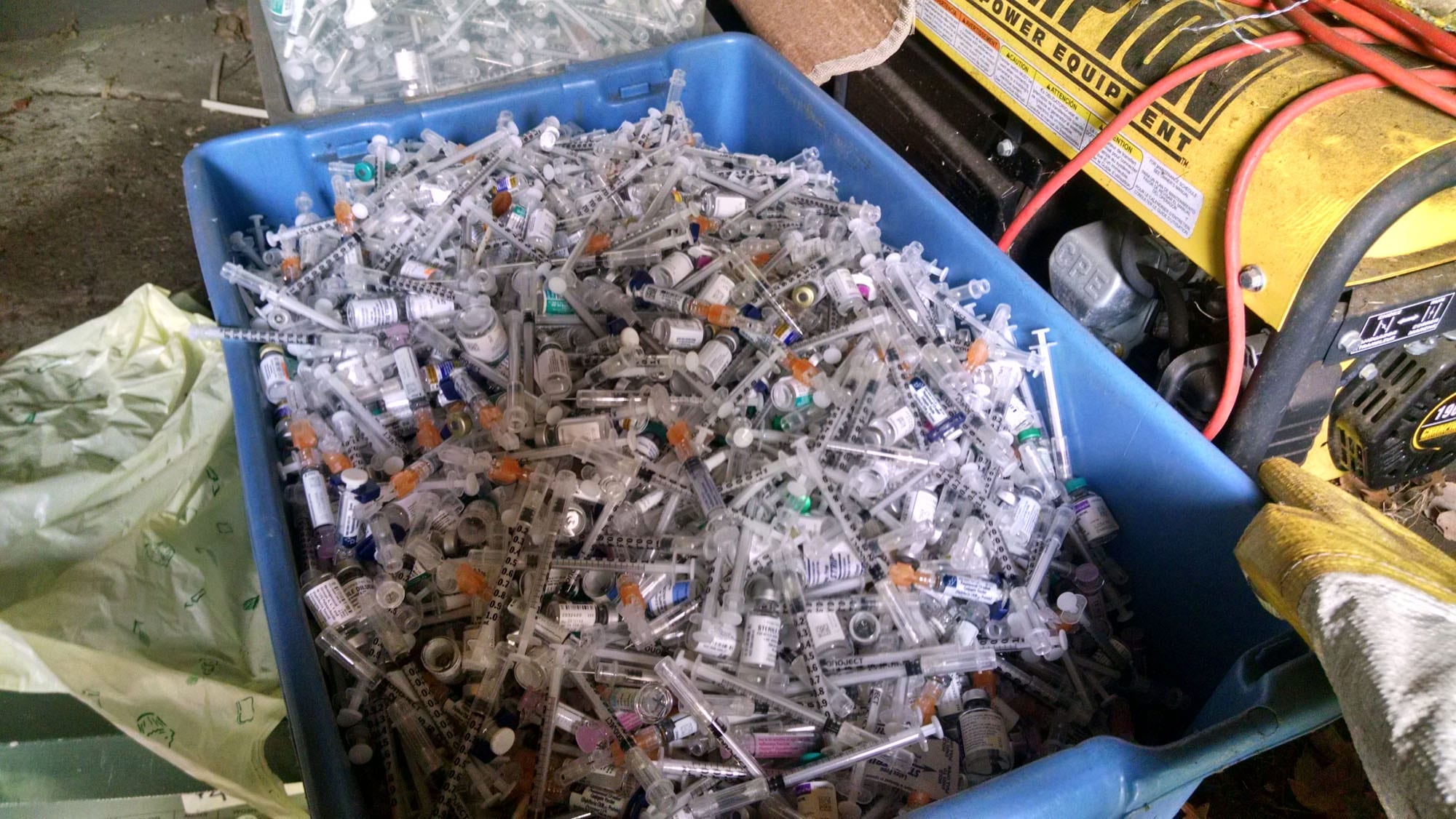 Overflowing container of used syringes and vials